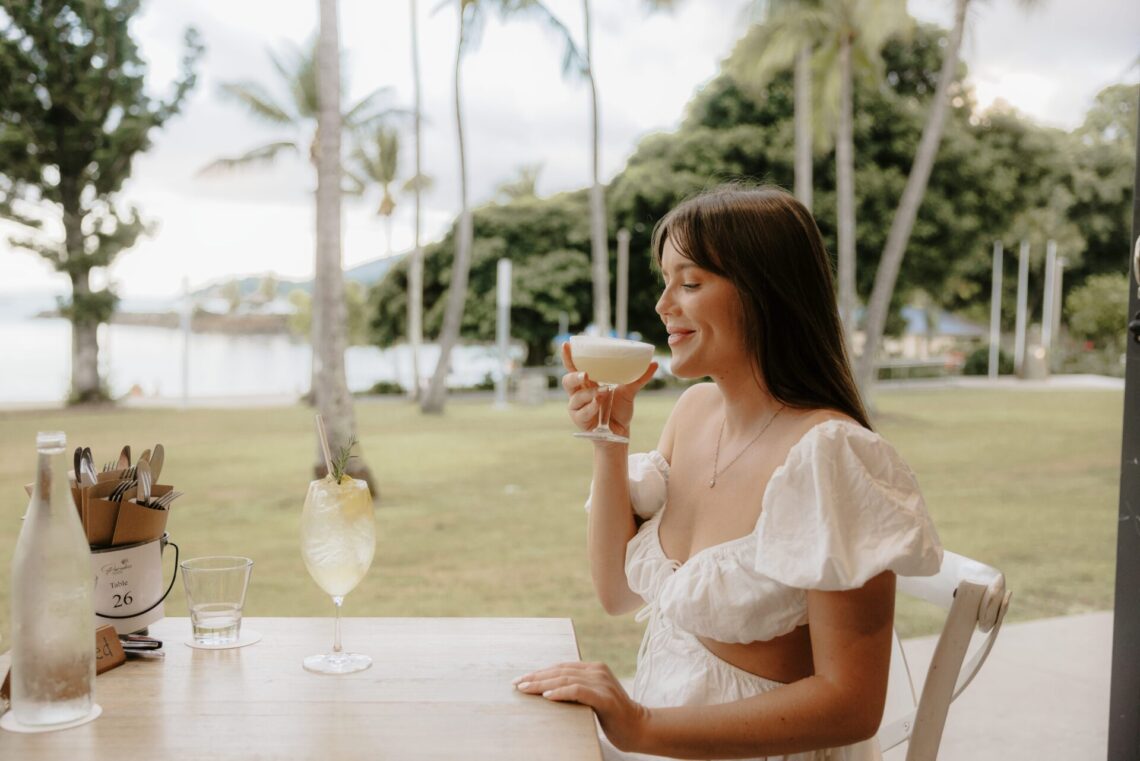 Lady enjoying a cocktail at a rooftop bar overlooking the ocean