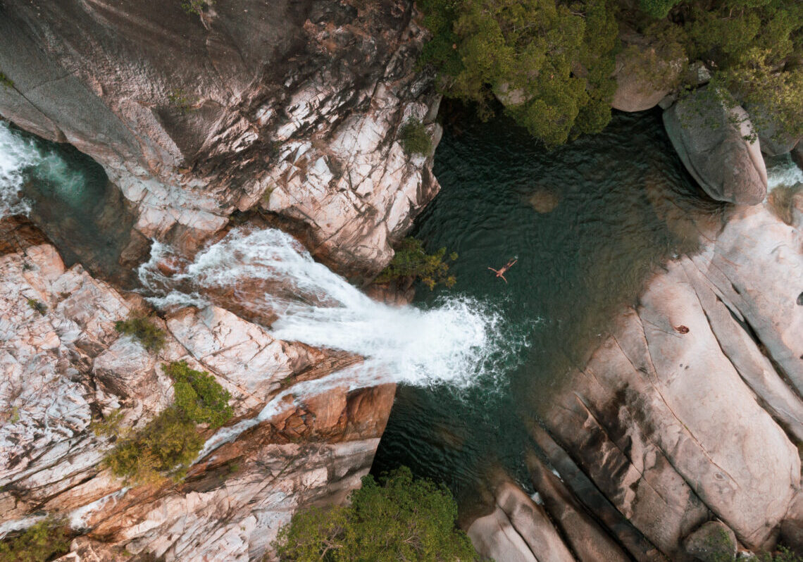 Aerial image of man floating in swimming hole at the bottom on Emerald Creek Falls near Mareeba. Photo by Mitchell Cox